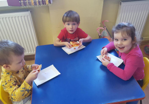 Dzieci zjadają pizzę ze smakiem.